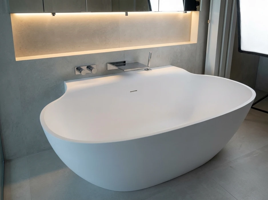 Baignoire îlot autoportante de design contemporain, en solid surface blanc mat, forme organique asymétrique avec appui-tête intégré