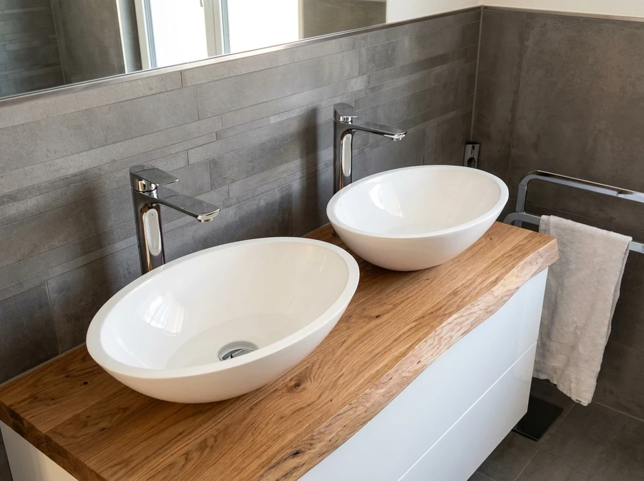 Salle de bain moderne avec double vasque à poser ovale en céramique blanche brillante, montées sur un plan de travail en chêne massif bord naturel