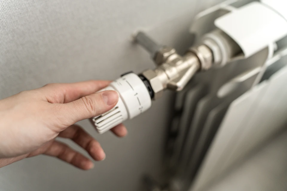 Plombier professionnel en tenue de travail bleue et blanche installant ou réparant un lavabo mural dans une salle de bain moderne